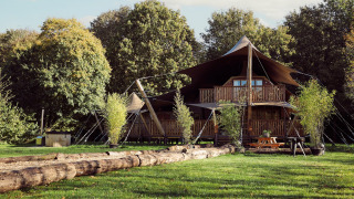 Glamping tent Hacienda at Resort de Parel in the Netherlands, surrounded by greenery and tall trees.