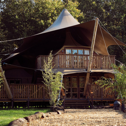 Tente de glamping safari de luxe avec balcon au Resort de Parel aux Pays-Bas, entourée de verdure.
