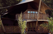 Elegante tienda de glamping tipo safari con balcón en Resort de Parel, Países Bajos, rodeada de vegetación.