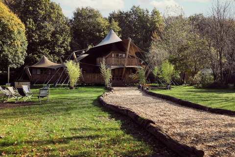 Tienda de glamping Hacienda en Resort de Parel, Países Bajos, rodeada de naturaleza y árboles verdes.