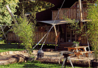 Glamping-Zelt Hacienda im Resort de Parel, Niederlande, mit Holzterrasse, Picknicktisch und Grill.