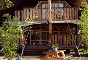 Glamping-Zelt Hacienda im Resort de Parel in den Niederlanden mit Holzterrasse und Picknicktisch.