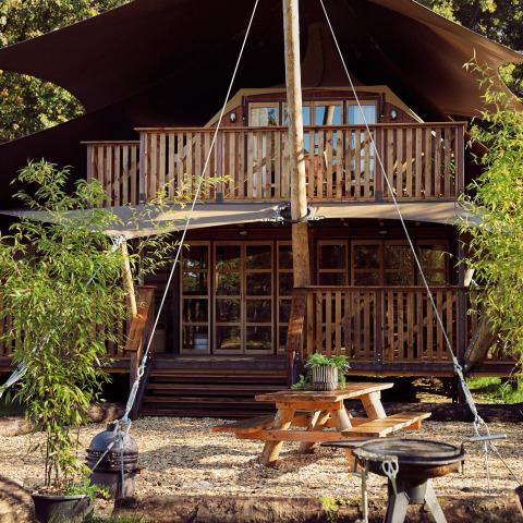 Glamping-Zelt Hacienda im Resort de Parel in den Niederlanden mit Holzterrasse und Picknicktisch.
