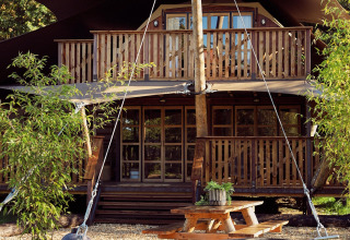 Tienda safari Hacienda para glamping en Resort de Parel, Países Bajos, con terraza de madera y picnic.