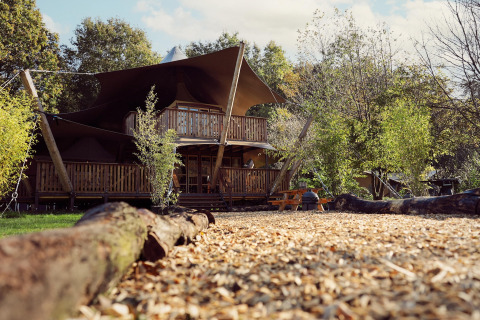 Safari-Glampingzelt Hacienda im Resort de Parel, Niederlande, mit Holzveranda und grüner Umgebung.