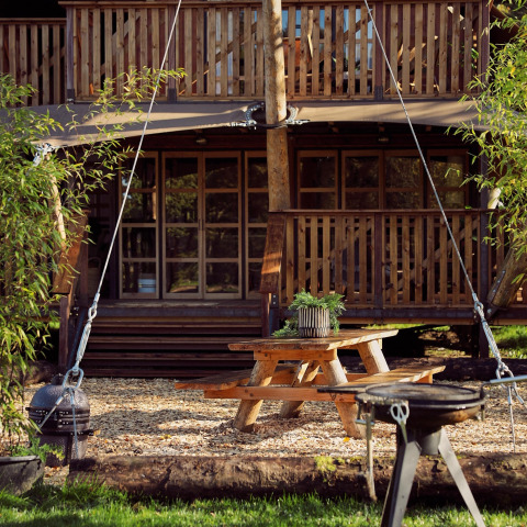 Udendørs spiseområde ved en luksuriøs glamping-telt Hacienda på Resort de Parel, Holland, omringet af træer.