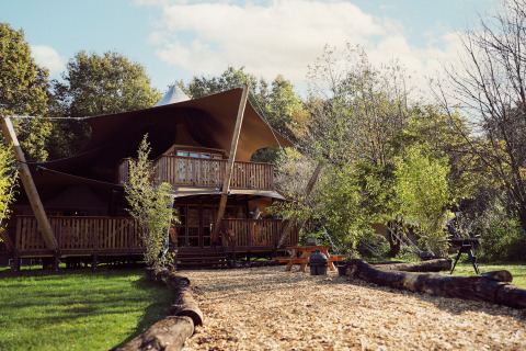 Glamping tent Hacienda, een safaritent bij Resort de Parel in Nederland, omgeven door groen en bomen.