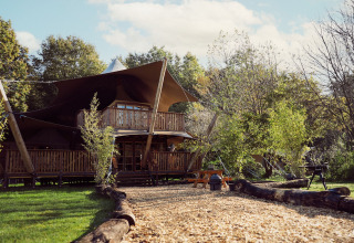 Tienda glamping Hacienda, una tienda safari en Resort de Parel, Países Bajos, rodeada de naturaleza verde.