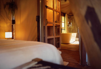 Innenaufnahme vom Glampingzelt Hacienda mit gemütlicher Beleuchtung und Badewanne im Resort de Parel, Niederlande.
