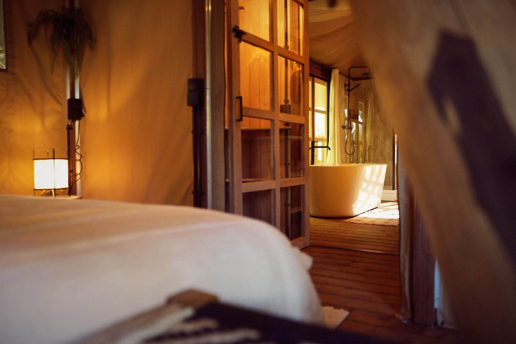 Interior de la lujosa tienda glamping Hacienda con bañera en Resort de Parel, Países Bajos, iluminada suavemente.