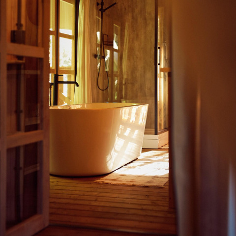 Baignoire élégante dans une tente glamping au Resort de Parel, Pays-Bas, baignée de lumière dorée.