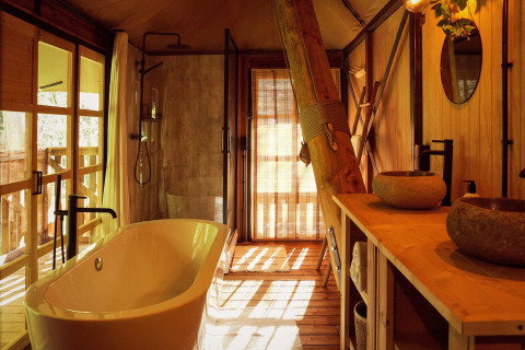 Baño de lujo en la tienda glamping Hacienda del Resort de Parel, con bañera exenta y detalles rústicos en madera.