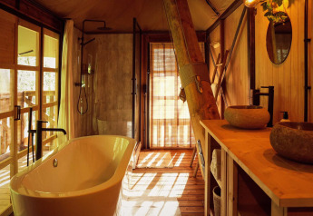 Luxuriöses Badezimmer im Glamping-Zelt Hacienda im Resort de Parel, mit freistehender Badewanne und Holzelementen.