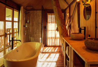 Salle de bain luxueuse dans la tente glamping Hacienda du Resort de Parel, avec baignoire et décoration en bois.