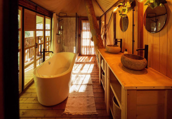 Luxuriöses Badezimmer im Safari-Glampingzelt mit freistehender Badewanne und Natursteinwaschbecken in Resort de Parel.