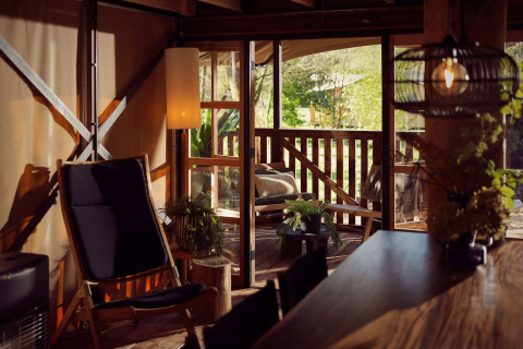 Indvendig udsigt over en glamping telt med hyggelig siddeplads og terrasse i naturen ved Resort de Parel.