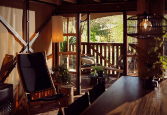 Indvendig udsigt over en glamping telt med hyggelig siddeplads og terrasse i naturen ved Resort de Parel.
