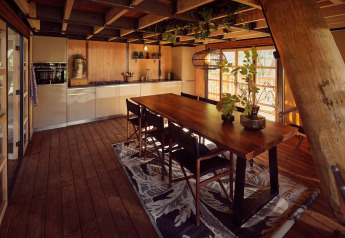 Gezellige keuken en eethoek in een glamping safaritent met houten vloer, planten en grote ramen.