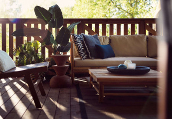 Gemütliche Safarizelt-Terrasse im Resort de Parel, Niederlande, mit Sofa, Pflanzen und Holztisch.
