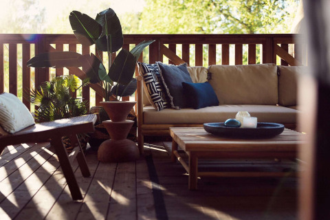 Gemütliche Safarizelt-Terrasse im Resort de Parel, Niederlande, mit Sofa, Pflanzen und Holztisch.