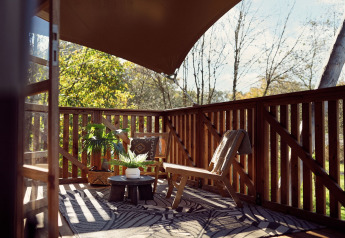 Sonnige Holzterrasse mit Stühlen und Pflanzen im Safari-Zelt Hacienda, Resort de Parel, Niederlande.