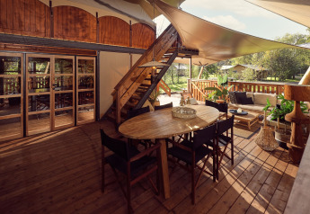 Luxuriöses Safari-Glamping-Zelt mit Holzterrasse, Sitzbereich und Pflanzen im Resort de Parel, Niederlande.