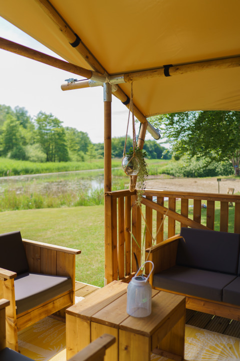 Gezellige zithoek in glampingtent La Vida Aqua bij Resort de Parel, Nederland, met zicht op vijver.