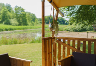 Gezellige zithoek in glampingtent La Vida Aqua bij Resort de Parel, Nederland, met zicht op vijver.