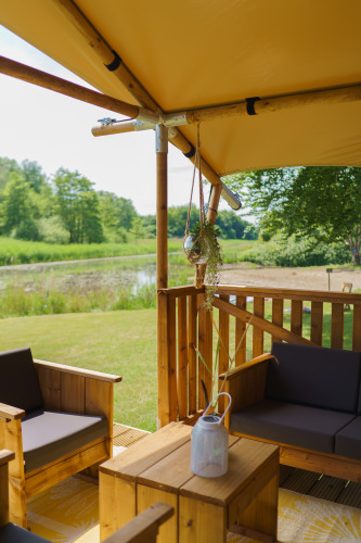 Cozy seating in glamping tent La Vida Aqua at Resort de Parel, Netherlands, overlooking a scenic pond.