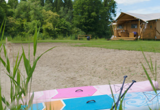 Safaritent La Vida Aqua met opblaasbare paddleboard en peddels op het zand bij Resort de Parel.
