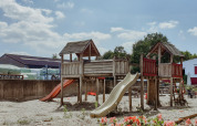 Spielplatz mit Holzstruktur und Rutschen bei sonnigem Wetter im Feather Down Hoeve Brugge, Westflandern.
