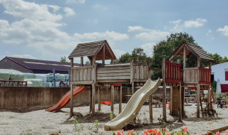 Parque infantil con estructuras de madera y toboganes bajo el sol en Feather Down Hoeve Brugge, Bélgica.