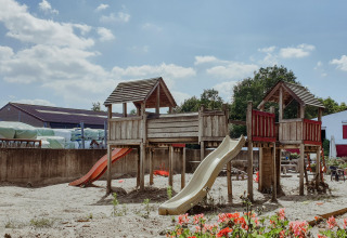 Playground with wooden climbing structures and slides on a sunny day at Feather Down Hoeve Brugge, Belgium.