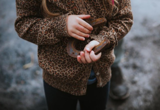 A child wearing a leopard print jacket holding a rusty horseshoe at Feather Down Hoeve Brugge, Belgium.