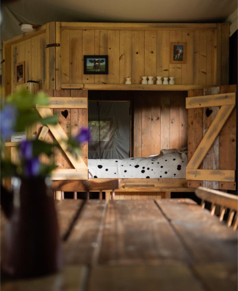 Acogedor interior de madera con mesa rústica, cama y flores en Feather Down Hoeve Brugge en Bélgica.