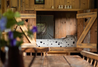 Gezellig houten interieur met een tafel en slaaphoek bij Feather Down Hoeve Brugge in West-Vlaanderen.
