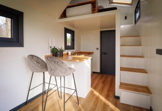 Intérieur moderne d'une tiny house avec cuisine, coin repas et mezzanine au Holiday Park Sallandshoeve, Pays-Bas.