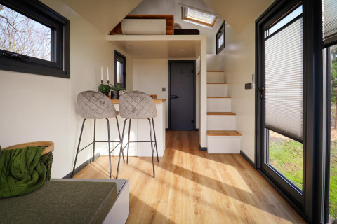 Interni di una tiny house moderna al Holiday Park Sallandshoeve, Paesi Bassi, con legno chiaro e grandi finestre.