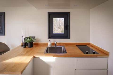 Moderne Küchenzeile in einem Tiny House im Holiday Park Sallandshoeve mit Holzarbeitsplatte und Fenster.