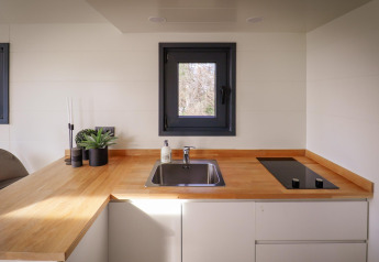 Rincón de cocina moderna en una tiny house en Holiday Park Sallandshoeve, Países Bajos, con encimera de madera.