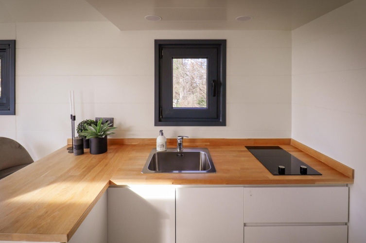 Rincón de cocina moderna en una tiny house en Holiday Park Sallandshoeve, Países Bajos, con encimera de madera.