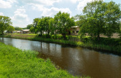 Vista de un río con césped, árboles y tiendas safari en Holiday Park Mölke, Países Bajos, durante un día soleado.