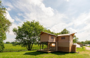 Safari treehouse tent with deck at Holiday Park Mölke in the Netherlands, surrounded by green fields.