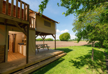 Tenda safari Treehouse con terrazza e vista sui campi al Holiday Park Mölke, Paesi Bassi, giornata di sole.