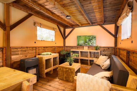 Knusse woonkamer in de Treehouse tent met houten meubels bij Holiday Park Mölke in Nederland.