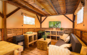 Gemütliches Wohnzimmer im Treehouse-Zelt mit Holzmöbeln und TV im Holiday Park Mölke, Niederlande.