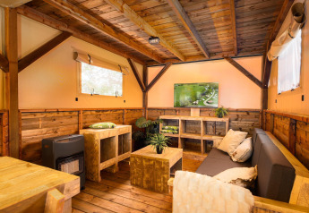Hyggelig opholdsstue i et Treehouse-telt med træmøbler og tv på Holiday Park Mölke i Nederlandene.