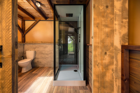 Baño moderno con acabados en madera, ducha y WC en una tienda safari en Holiday Park Mölke, Países Bajos.