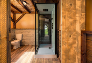 Moderne badkamer met houtaccenten, douche en toilet in een safaritent bij Holiday Park Mölke, Nederland.