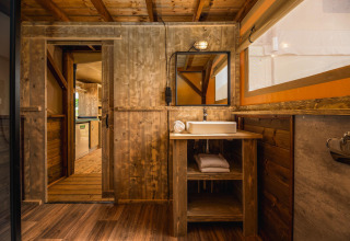 Rustikt badeværelse i safari-teltet Treehouse tent med vask, trævægge og håndklæder på Holiday Park Mölke.